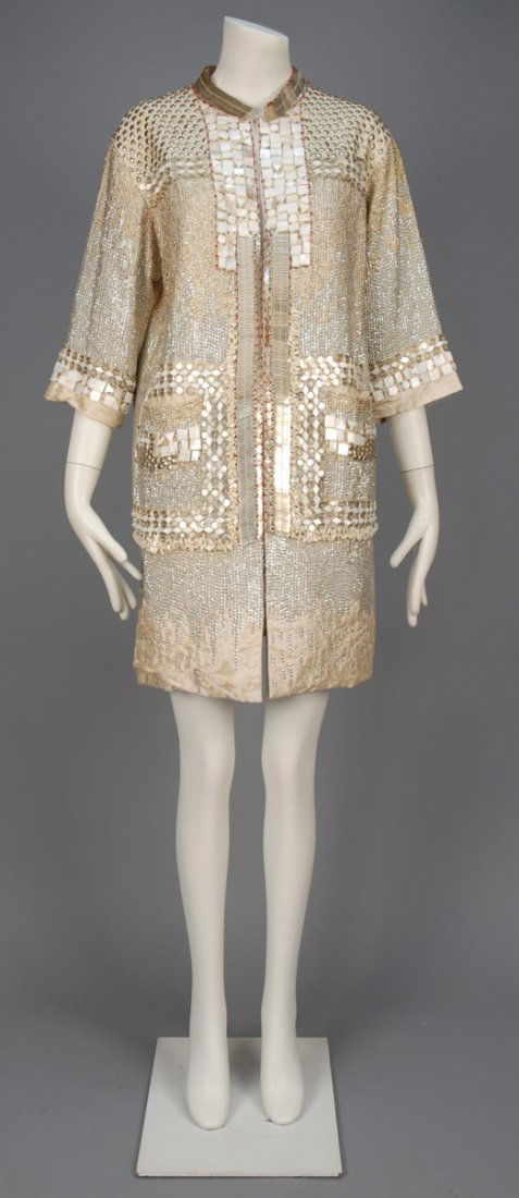 BLUMARINE MOSAIC SILK COAT.: Ivory silk jacquard having band collar, elbow length sleeve and patch pockets, decorated allover with metallic disks, rings and studs, geometric mother of pearl trim, etc. Labeled. B-42, Sh-17, L-37 1