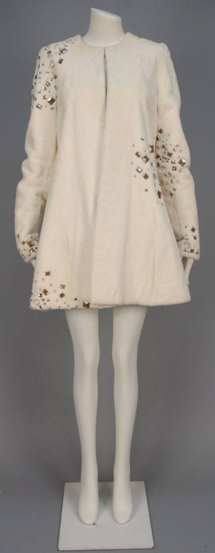 HALSTON JEWELED FUR COAT.: White collarless trapeze style having asymmetrical decoration of faceted rhinestones, smoky lucite squares and silver drops. Labeled. B-36, Sh-16, Slv-28, L-35. Excellent.