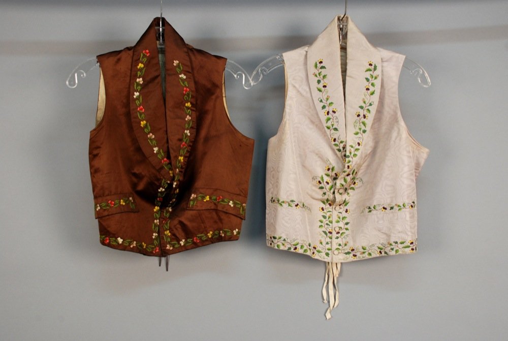 TWO GENTS SILK EMBROIDERED WAISTCOATS, 19th C. Both: TWO GENTS SILK EMBROIDERED WAISTCOATS, 19th C. Both with shawl collar and polychrome vining floral: One grey moire faille with self buttons, Ch-40, L-21, (faint underarm stains). One brown satin with 