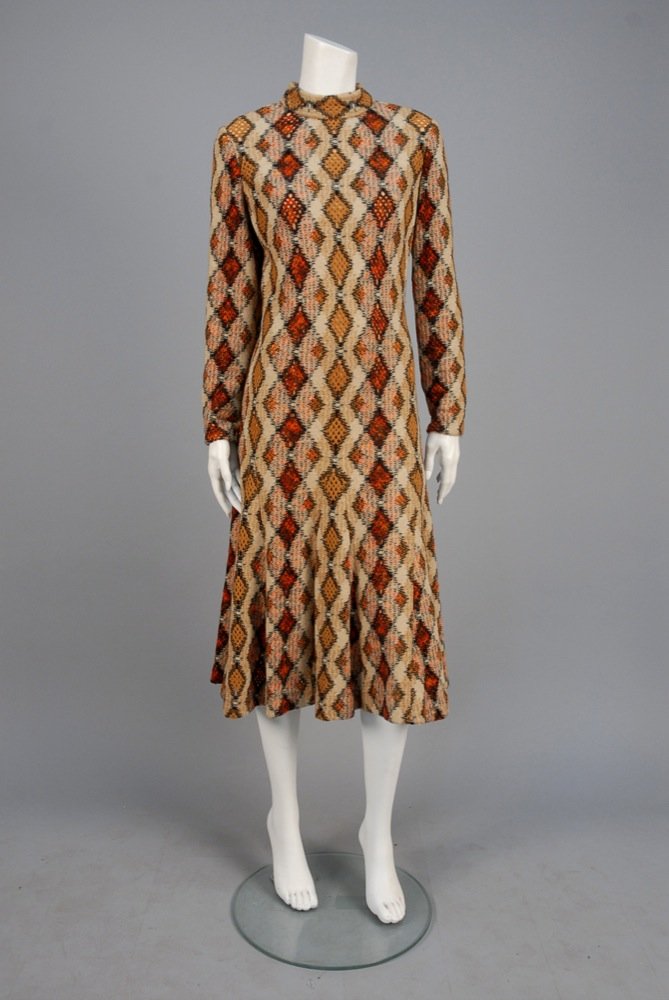CHRISTIAN DIOR WOOL DAY DRESS, 1970s. Polychrome: CHRISTIAN DIOR WOOL DAY DRESS, 1970s. Polychrome novelty weave argyle variant with openwork diamonds having long sleeve, band collar and trumpet flared mid-calf skirt, nude silk crepe under-dress. New