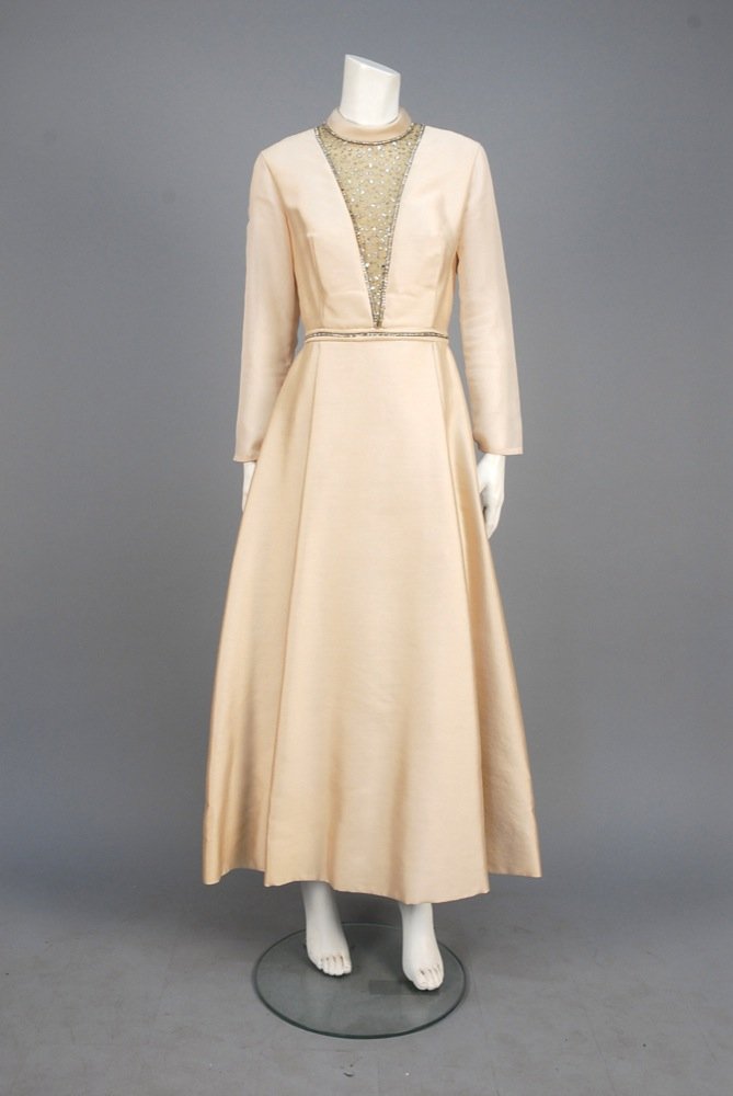 RHINESTONE DECORATED EVENING DRESS, 1970s. Heavy weave: RHINESTONE DECORATED EVENING DRESS, 1970s. Heavy weave ivory silk with folded band collar and long sheer sleeve, sheer V-shaped bodice insert bordered and studded with prong-set rhinestones in varied 
