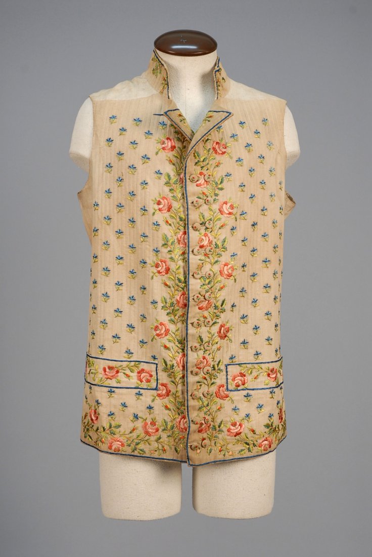GENTS FLORAL EMBROIDERED COTTON WAISTCOAT, LATE 18th -: Tan with patterned vertical rib having stand collar, narrow double breast with small lapel and wide pocket band, decorated with pink and green satin stitch roses on a ground of blue posies, embroidere