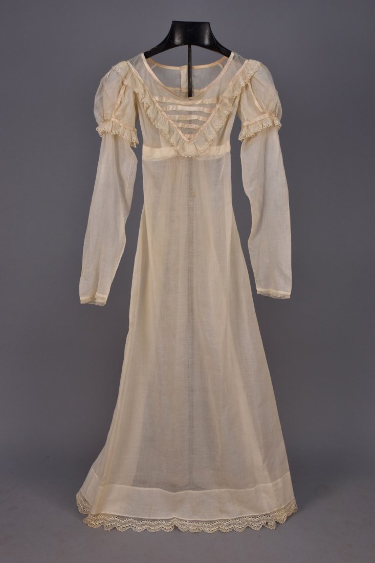REGENCY EMBROIDERED COTTON GOWN.: White mull having long sleeve with lace edge, puffed cap decorated with silk ribbon and embroidered ruffle, V-front empire bodice with ribbons and ruffle, bodice and skirt back gathered into waistband