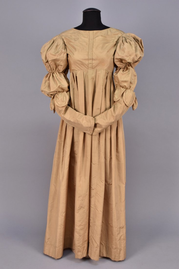 BROWN SILK TAFFETA DRESS, 1830-1835.: Probably British, boatneck empire bodice pleated into a center band, long sleeve having double puff above self petals, pleated skirt. B-30, high W-24, L-53. (Underarm stains, spot on sleeve, scattered