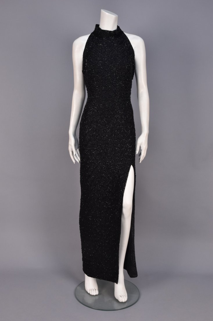 BEADED SILK EVENING SHEATH, 1980s.: Sleeveless black chiffon with band collar and angled arm openings, the bodice decorated with small scallops of black seed, bugle and larger black beads, the skirt having larger scallops in bugle beads