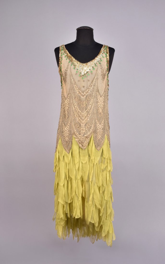 METALLIC LACE and CHIFFON DRESS with SEQUINS , 1920s: Sleeveless bodice of cotton net and metallic gold lace over nude chiffon, trimmed with gold sequins and hanging green glass baubles, ending at the hip in a series of points, chartreuse chiffon skirt c