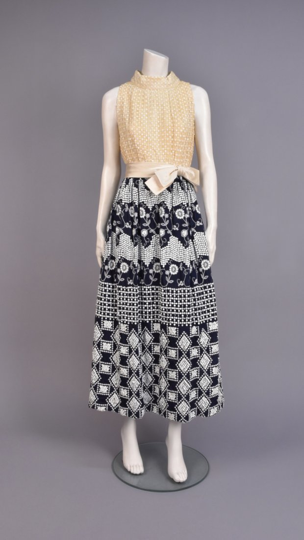 SEQUINED and EMBROIDERED SUMMER GOWN, c. 1970: Sleeveless bodice of cream voile having a lattice of embroidered flower heads and white sequins, set-in waist with satin bow sash, full black voile skirt decorated with white sequins and yarn embroide