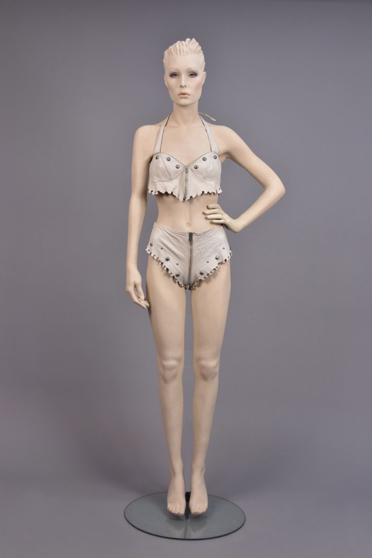 STUDDED LEATHER BIKINI with OPTIONAL THONG, 1980s: Off-white hide with zip front halter top having silver studs and scalloped edge, matching zip-front bottom with back laces, optional thong with leather ties. Unlabeled, sold to Gene by the model Janic