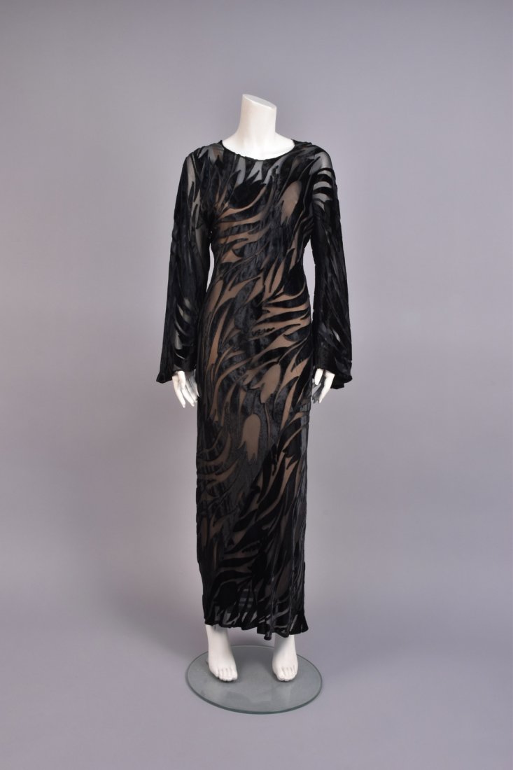 HALSTON BLACK VOIDED VELVET GOWN: Bias-cut silk velvet voided to chiffon in a pattern of tulips, having long bell sleeve, jewel neck and keyhole back, chiffon underdress. Labeled. B-40, W-36, H-40, L-56 1/2. Excellent. GLC