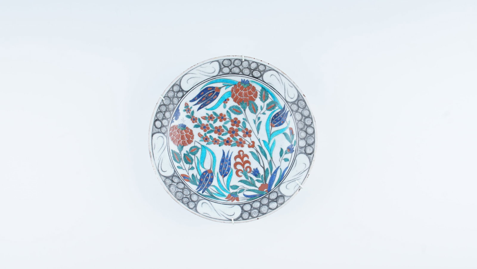 A RARE POLYCHROME IZNIK POTTERY DISH (CIRCA 1575–1590): This finely executed polychrome Iznik pottery dish represents the celebrated “Golden Age” of Ottoman ceramic production, dating to the late 16th century (circa 1575–1590). The white fritware