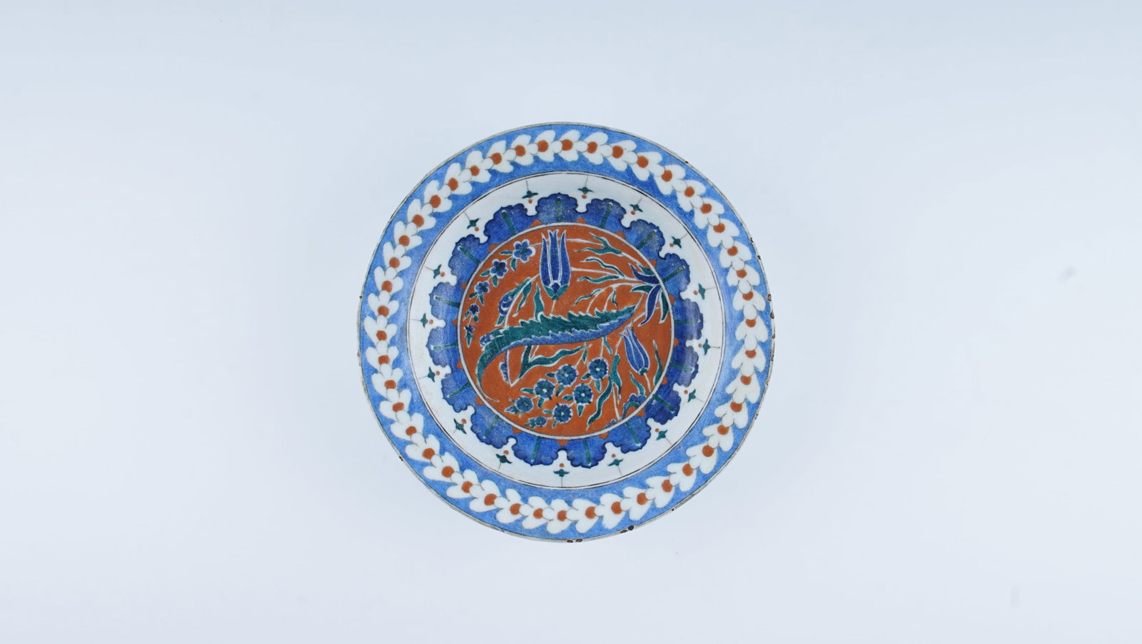 AN IMPORTANT POLYCHROME IZNIK POTTERY DISH (CIRCA 1575–1585): This finely executed deep-form polychrome Iznik dish belongs to the celebrated “Golden Age” of Ottoman ceramic production, dating to circa 1575–1585. The creamy-white fritware body is decora