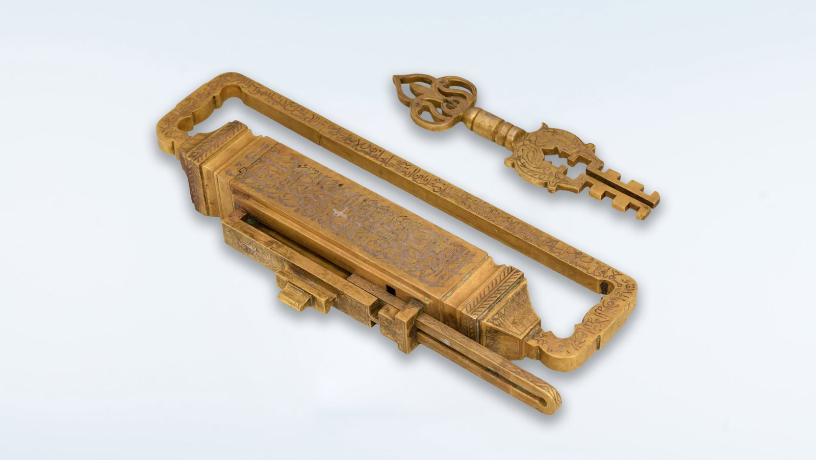 A MONUMENTAL OTTOMAN GILT BRONZE LOCK AND KEY WITH QUR’ANIC CALLIGRAPHY, 19TH CENTURY: A monumental and highly impressive Ottoman gilt bronze lock and key set, dating to the 19th century, distinguished by its exceptional scale, weight, and intricate construction. The surfaces are richly