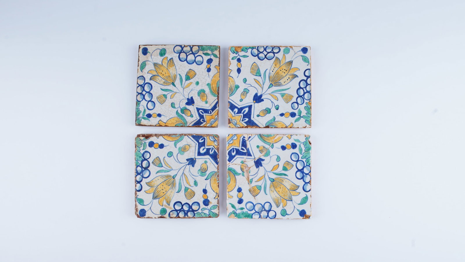 A FINE SET OF FOUR POLYCHROME POTTERY TILES PROBABLY DUTCH DELFT, LATE 17TH / EARLY 18TH CENTURY: A fine set of four polychrome pottery tiles decorated with a vibrant floral composition, executed in the Delft manner. The design features stylized blossoms and scrolling foliage rendered in a lively 