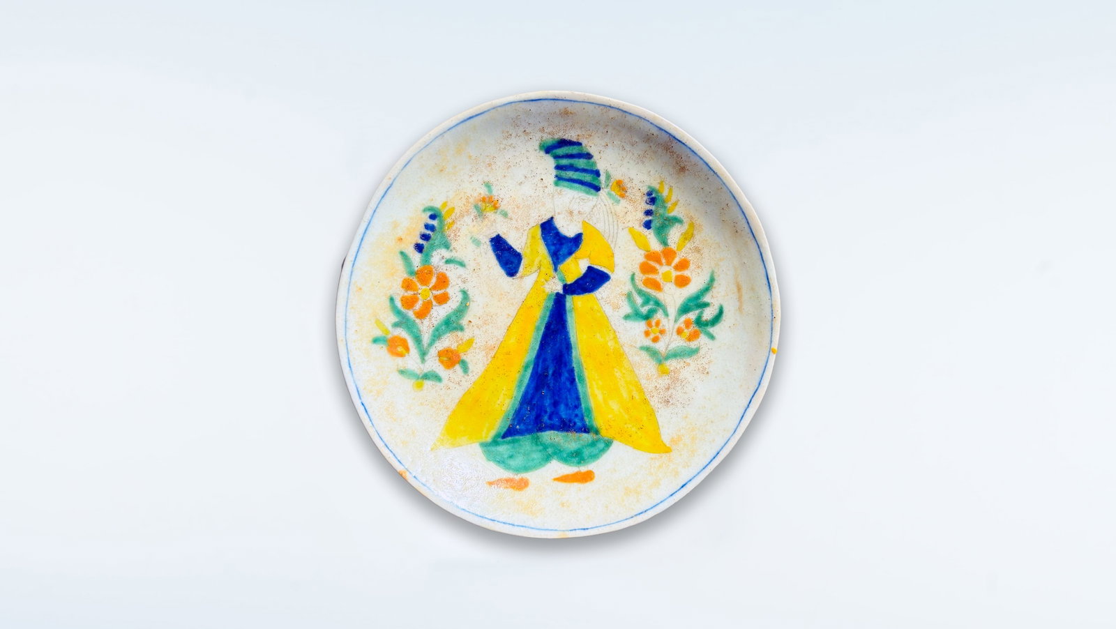 FINE OTTOMAN KÜTAHYA FIGURAL POTTERY PLATE, 18TH CENTURY: An Ottoman Kütahya polychrome figural pottery plate, decorated in underglaze on a white ceramic body, dating to the 18th century. The composition is centered by a stylized standing figure, possibly r