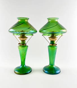Loetz Green Iridescent Glass Oil Lamps with Swirled Pattern: Oil lamps featuring green iridescent art glass attributed to Loetz, with a swirled pattern throughout the bases and glass shades. Each lamp includes a central brass burner assembly with a crown-style