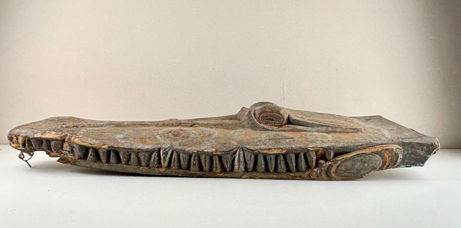Wooden Crocodile Canoe Prow from Papua New Guinea: Carved wooden crocodile canoe prow originating from Papua New Guinea. Features intricate detailing with painted accents in earth tones. The piece showcases a crocodile head motif with carved teeth, ci