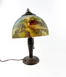 Handel Table Lamp with Reverse Painted Glass Shade (627): Handel signed table lamp featuring a painted glass shade depicting a serene outdoor scene with a cottage, trees, and a pond. The shade is capped with a decorative perforated metal fitter. The cast met
