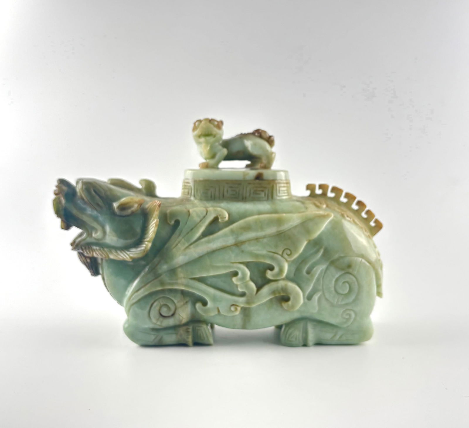 Jadeite Pixiu Censer with Fu Lion Lid, 20th Century: Jadeite censer intricately carved in the form of a Pixiu, a mythical creature symbolizing wealth. The vessel features fluid swirling motifs along its body, a hollowed center, and a detailed Fu Lion se