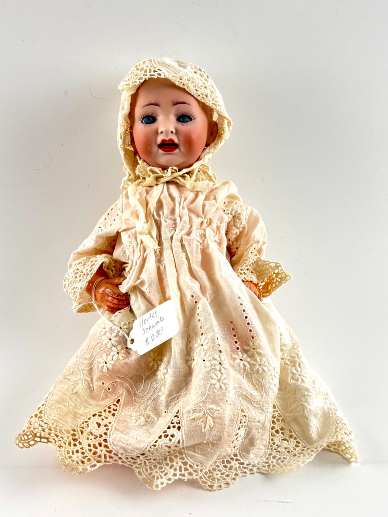 Hertel Schwab Bisque Head Baby Doll with Lace Outfit: Bisque head baby doll marked on the back of the head, attributed to Hertel Schwab. Features blue glass sleep eyes and an open mouth with teeth. Comes dressed in an off white lace outfit and bonnet. Co