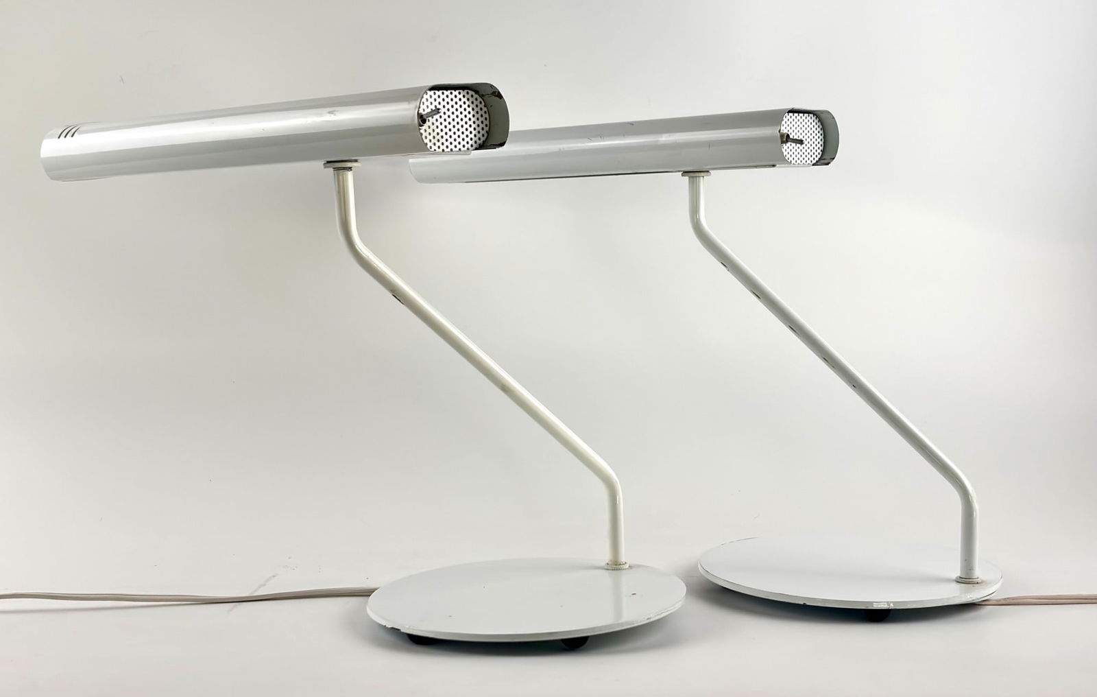 Underwriters Laboratories Desk Lamps in White, MCM: White mid century modern desk lamps by Underwriters Laboratories, marked with Issue No. AD 613. Each lamp features a cylindrical light head with perforated metal detail and a toggle switch, a tubular