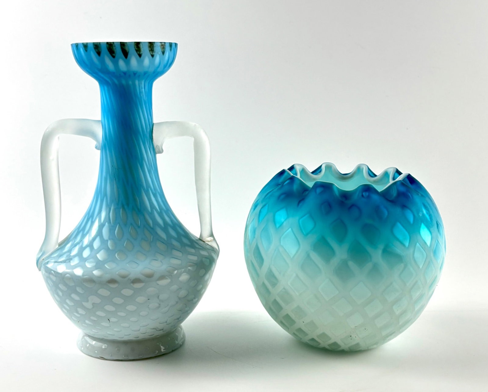 Murano Glass Vessels with Lattice Pattern by KB: Murano glass vessels featuring a blue and white graduated lattice pattern. Includes a handled vase with flared rim and applied frosted handles, and a bowl with a scalloped rim. Both pieces bear visibl