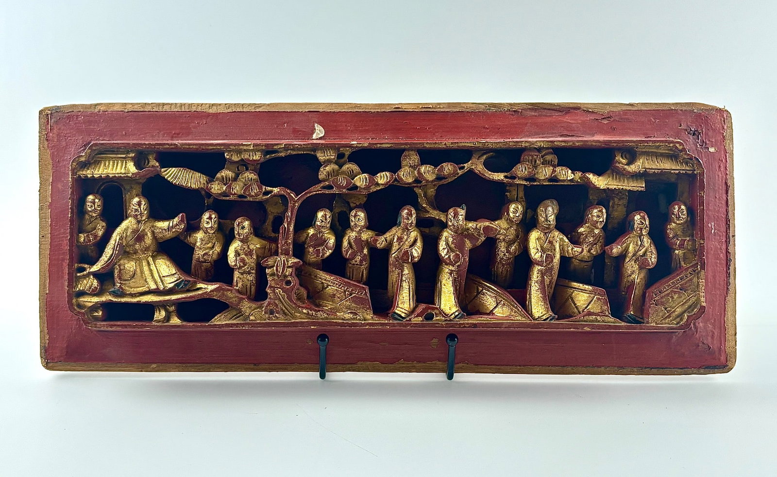 Antique Chinese Carved Wooden Panel with Gilt Figures: Rectangular hand carved wooden panel featuring intricately detailed Chinese figures in relief, coated with a gilt finish. The scene includes individuals engaged in various activities under trees and p