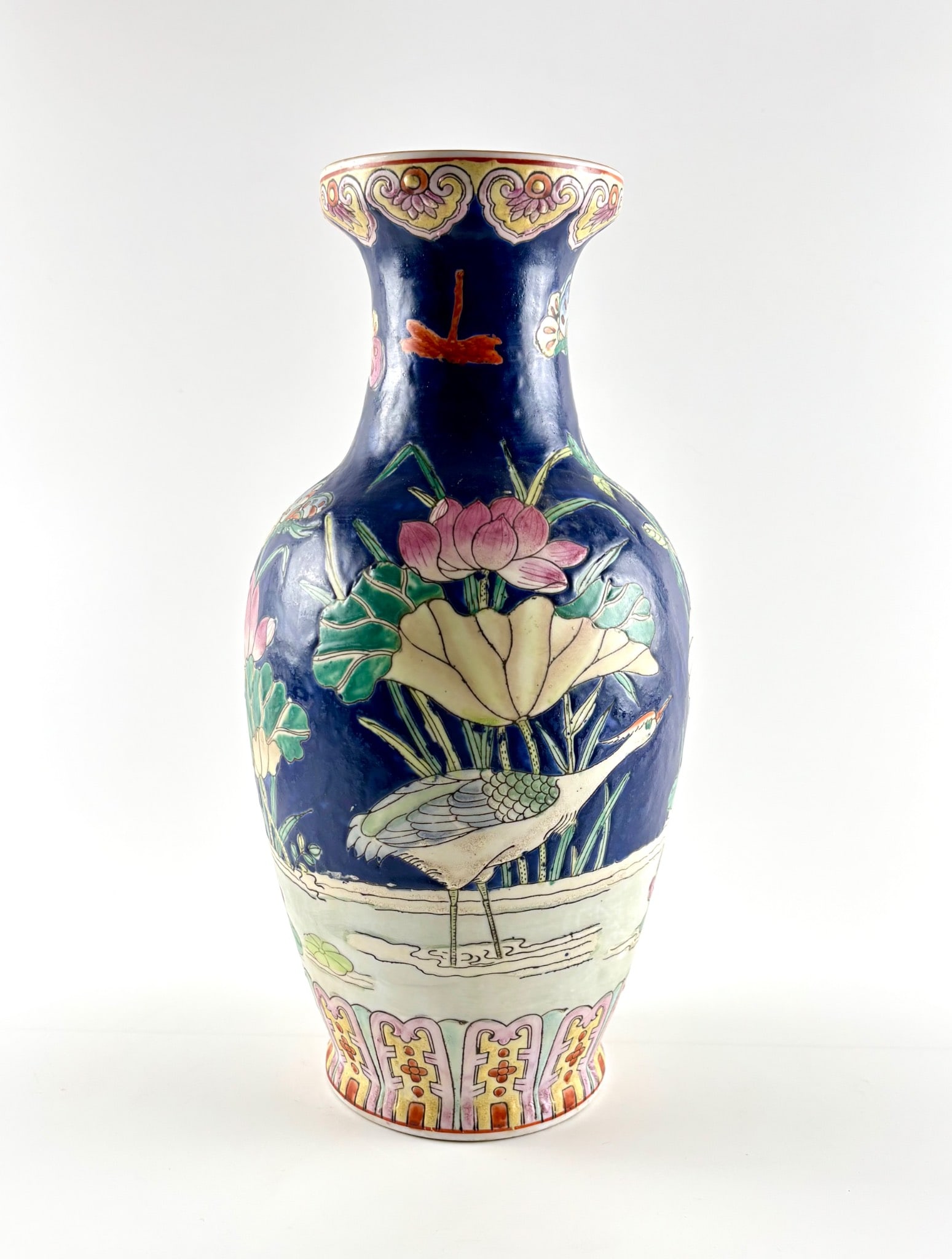 Hand Painted Cobalt Ground Ceramic Vase with Apocryphal Qianlong Mark: A hand painted ceramic vase with a cobalt blue ground, featuring vibrant depictions of cranes, lotus flowers, and natural elements. The flared rim and decorative motifs on the lower section enhance it