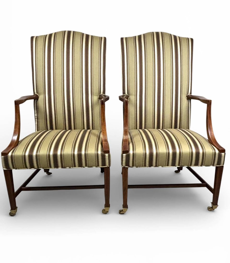 Kittinger Williamsburg Lolling Chairs with Jim Thompson Upholstery: Lolling chairs by Kittinger, featuring an elegantly carved wooden frame on casters with slight wear on the arms and legs. Chairs are upholstered in striped Jim Thompson fabric in shades of gold, brown