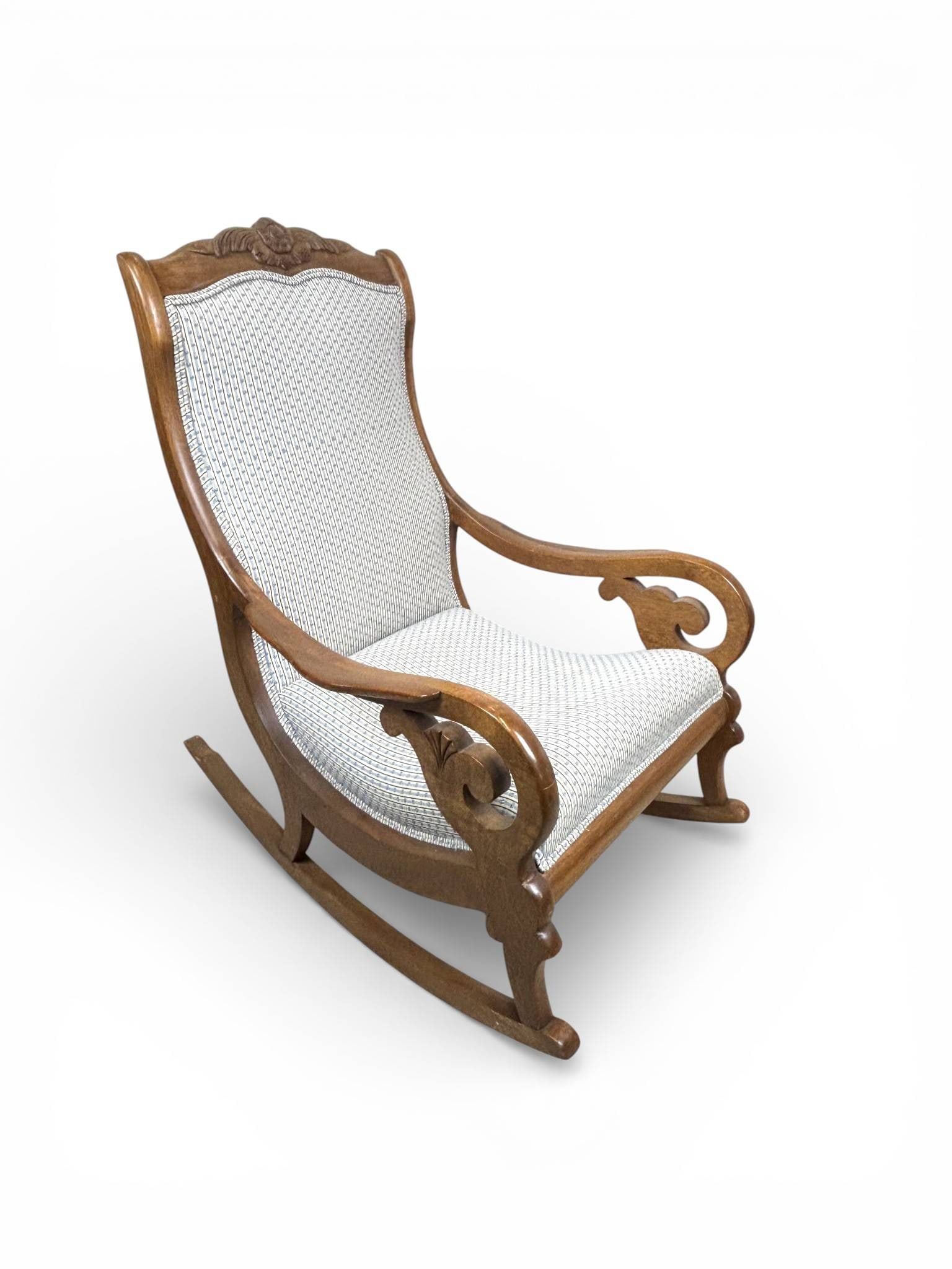 Handmade Walnut Victorian Rocking Chair with Carved Details, Circa 1880s: Handcrafted walnut rocking chair, circa 1880s, featuring a tall, contoured back with a carved crest rail. Scrolled arms with foliate carving flow seamlessly into the curved rocker base. Upholstered