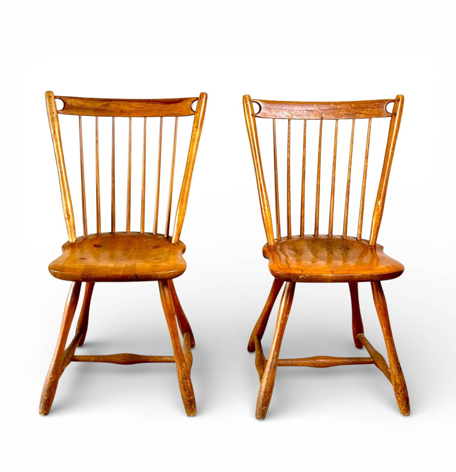 Early American Craft Guild Spindle Back Wooden Chairs: Spindle back chairs crafted by the Early American Craft Guild. Constructed from hardwood, featuring contoured wooden seats with visible joinery and spindle backs. Each chair rests on gently curved