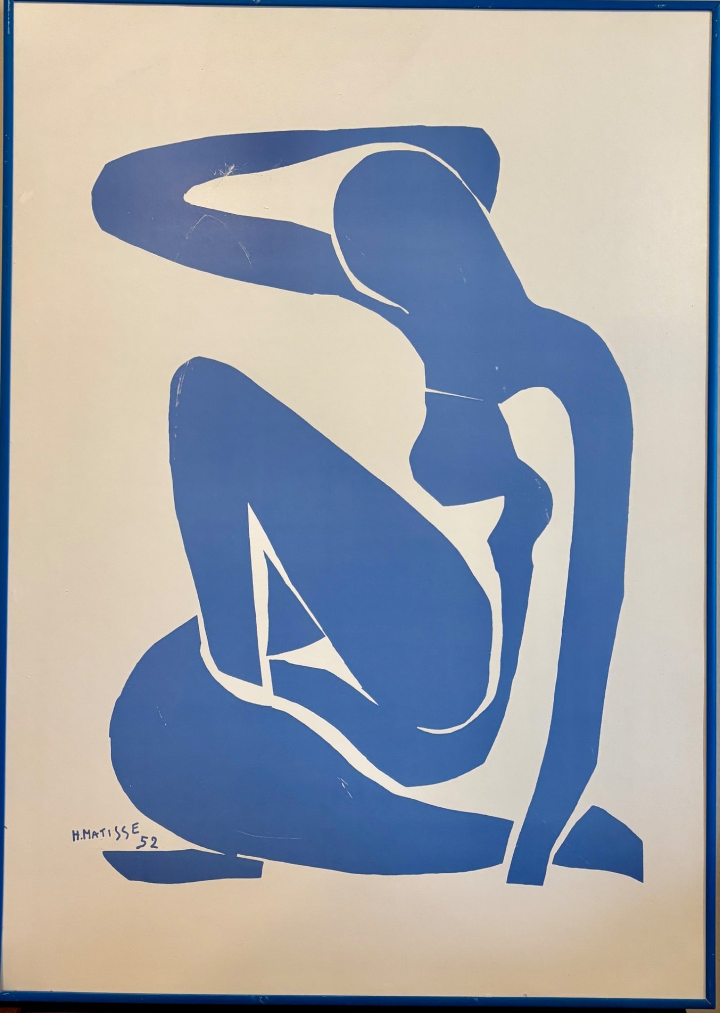 Framed Print of Henri Matisse’s Blue Nude II: Reproduction of Henri Matisses Blue Nude II, featuring a cut-paper collage style female figure in blue against an off white background. Signed H. Matisse 52 in the bottom left corner. Printed