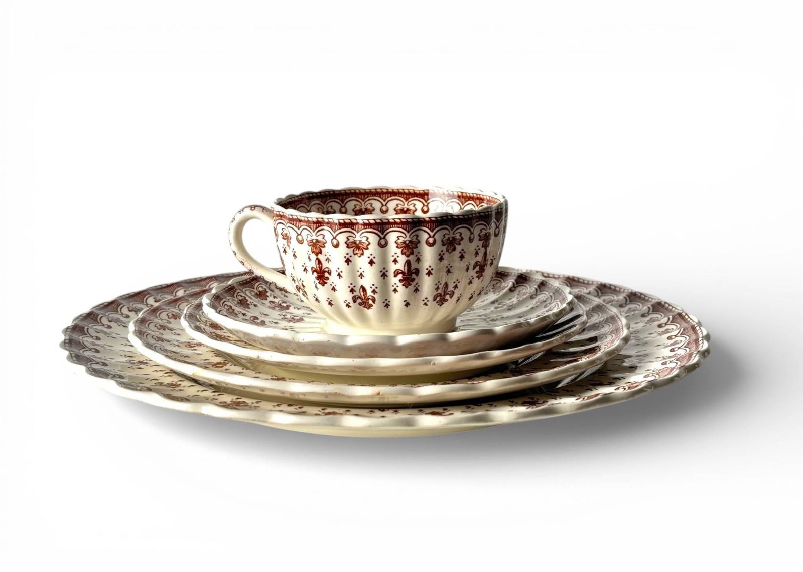 13 Five Piece Place Settings of Spode Copeland Fleur de Lys China: 65 pieces of Spode Copeland Fleur de Lys dinnerware in brown and cream. Comprising 13 place settings, each including a dinner plate, salad plate, bread plate, teacup, and saucer. Features scalloped ed