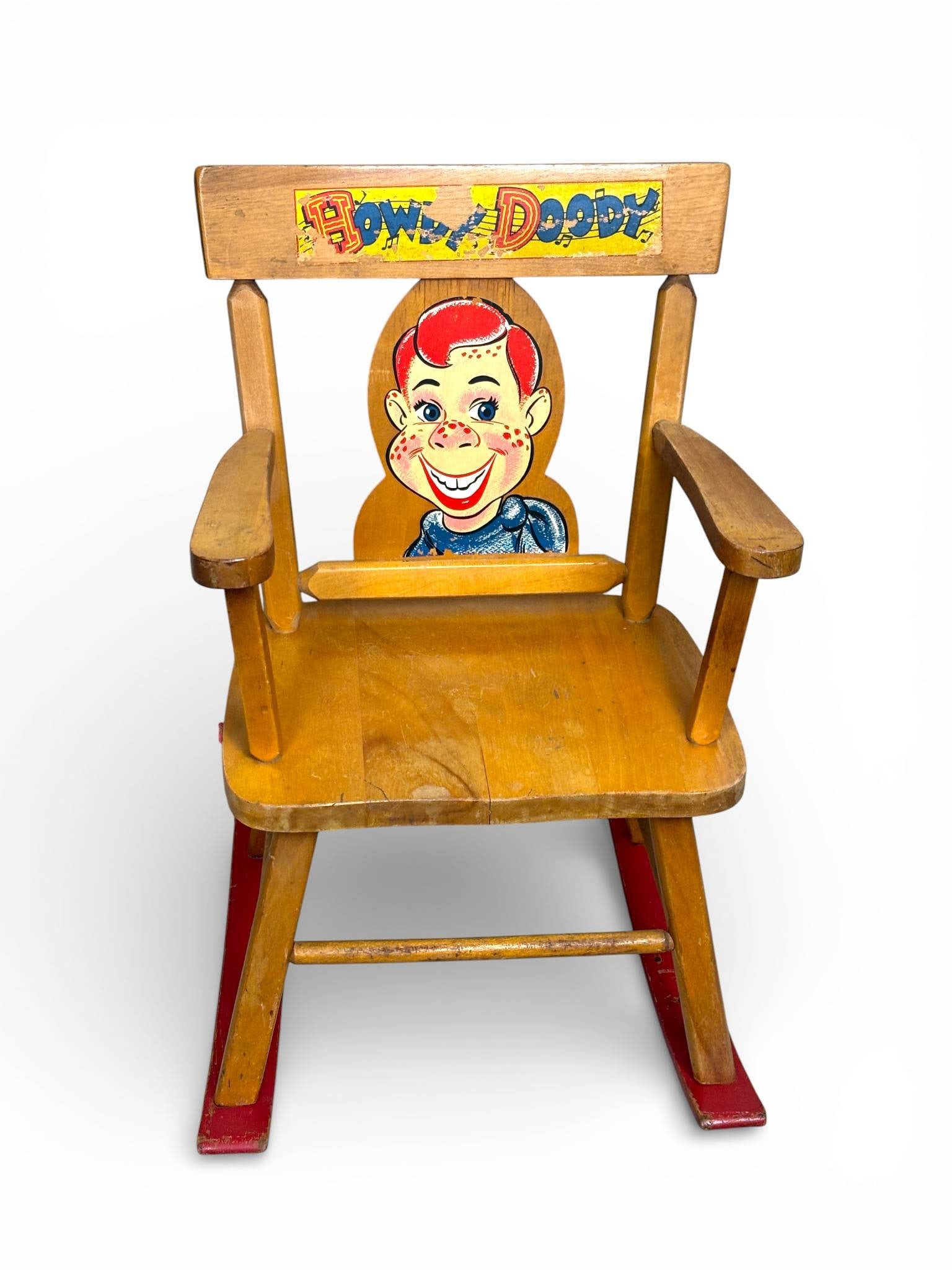 Howdy Doody Wooden Musical Rocking Chair: Wooden rocking chair featuring colorful Howdy Doody graphics on the backrest and top rail. Constructed of a light wood finish with red painted rockers. Music box originally installed beneath the seat