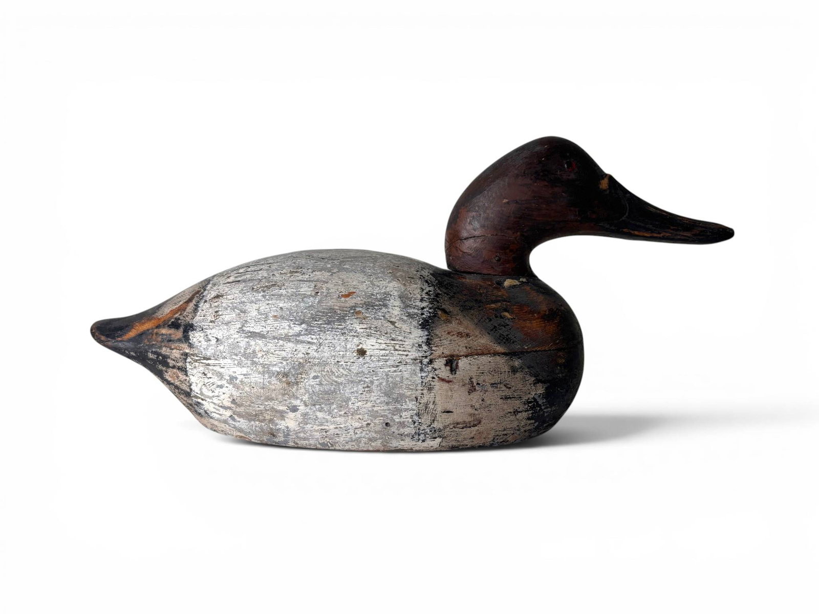 Primitive Folk Art Carved and Branded Duck Decoy: Hand carved and painted wooden duck decoy featuring a dark red brown head, black detail on the tail, and a weathered gray body. Distinct tool marks and branded inscriptions visible on the underside.