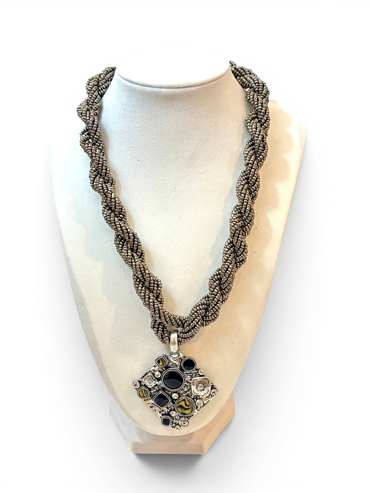 Twisted Metallic Rope Necklace with Multigem Pendant: Twisted metallic rope-style necklace featuring a square pendant adorned with various gemstone elements in black, yellow-striped, and clear tones, as well as decorative metalwork. The pendant presents 