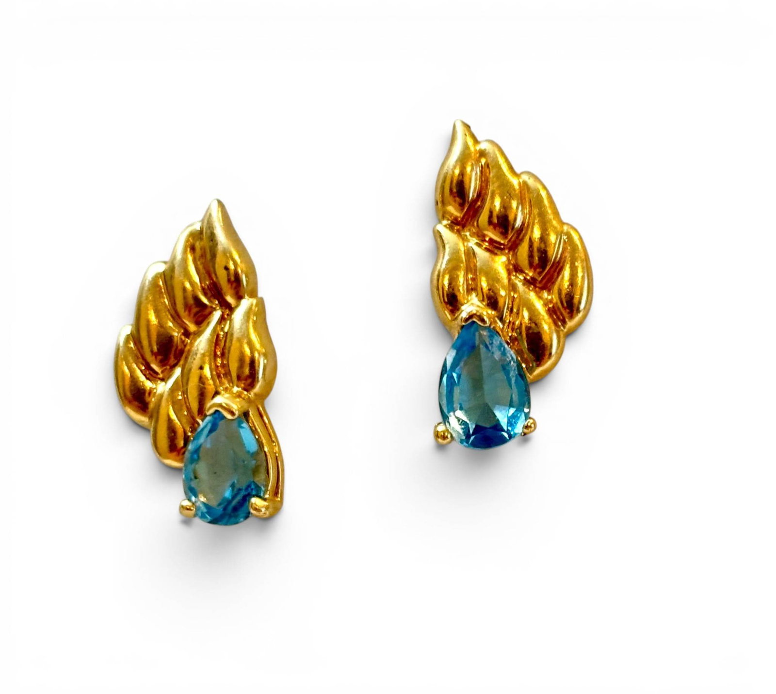 Pierced Earrings with Pear-Cut Blue Topaz Stones: Pierced earrings featuring pear-cut blue topaz stones set in gold-tone metal. The earrings exhibit a sculptural leaf-like design at the top, transitioning into a prong-set blue topaz drop at the base.