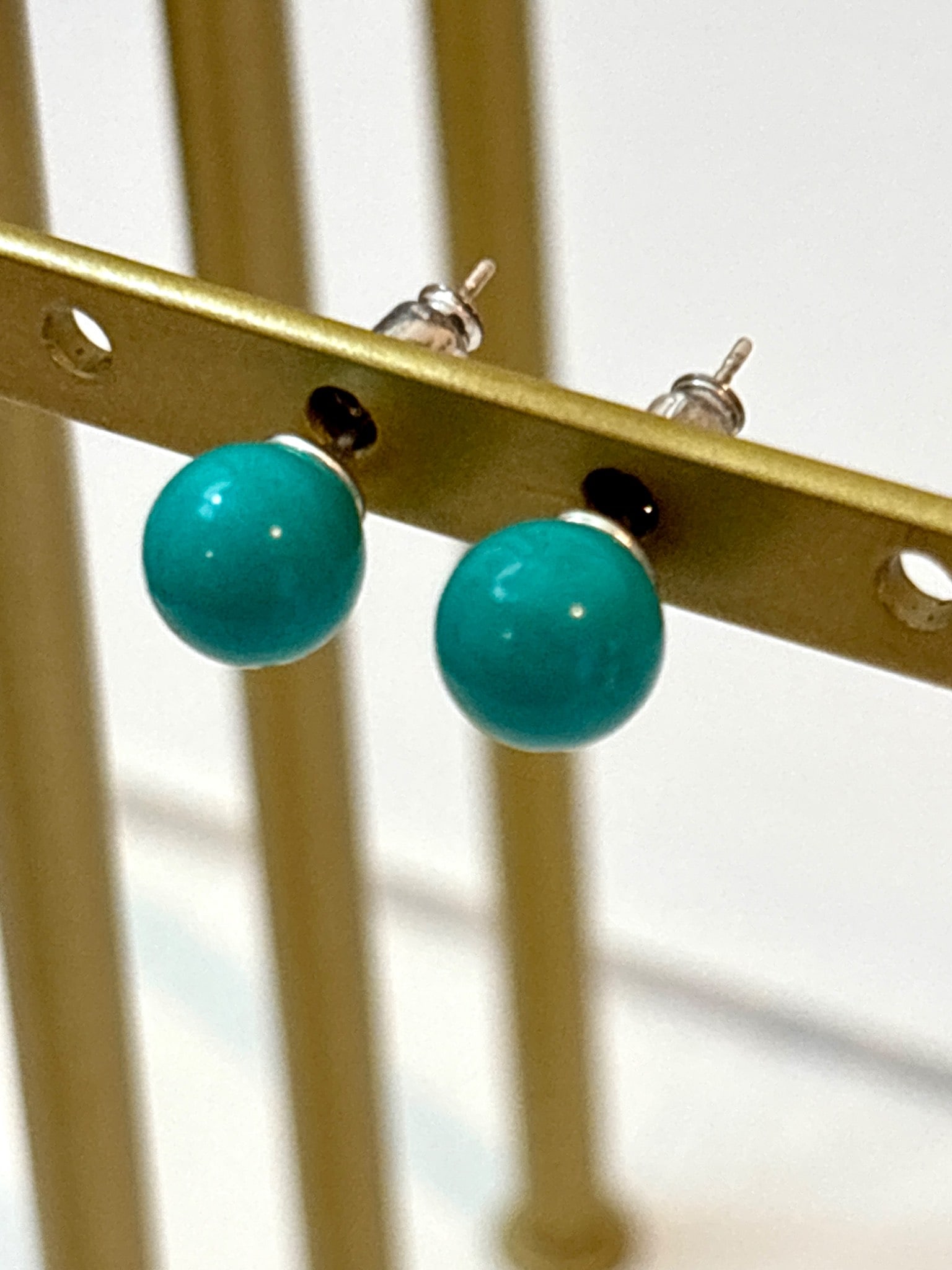 Sterling Silver Stud Earrings with Turquoise: Stud earrings featuring turquoise spherical cabochons set in sterling silver. The earrings include matching sterling silver posts and butterfly backings for secure wear. The turquoise exhibits a unifo