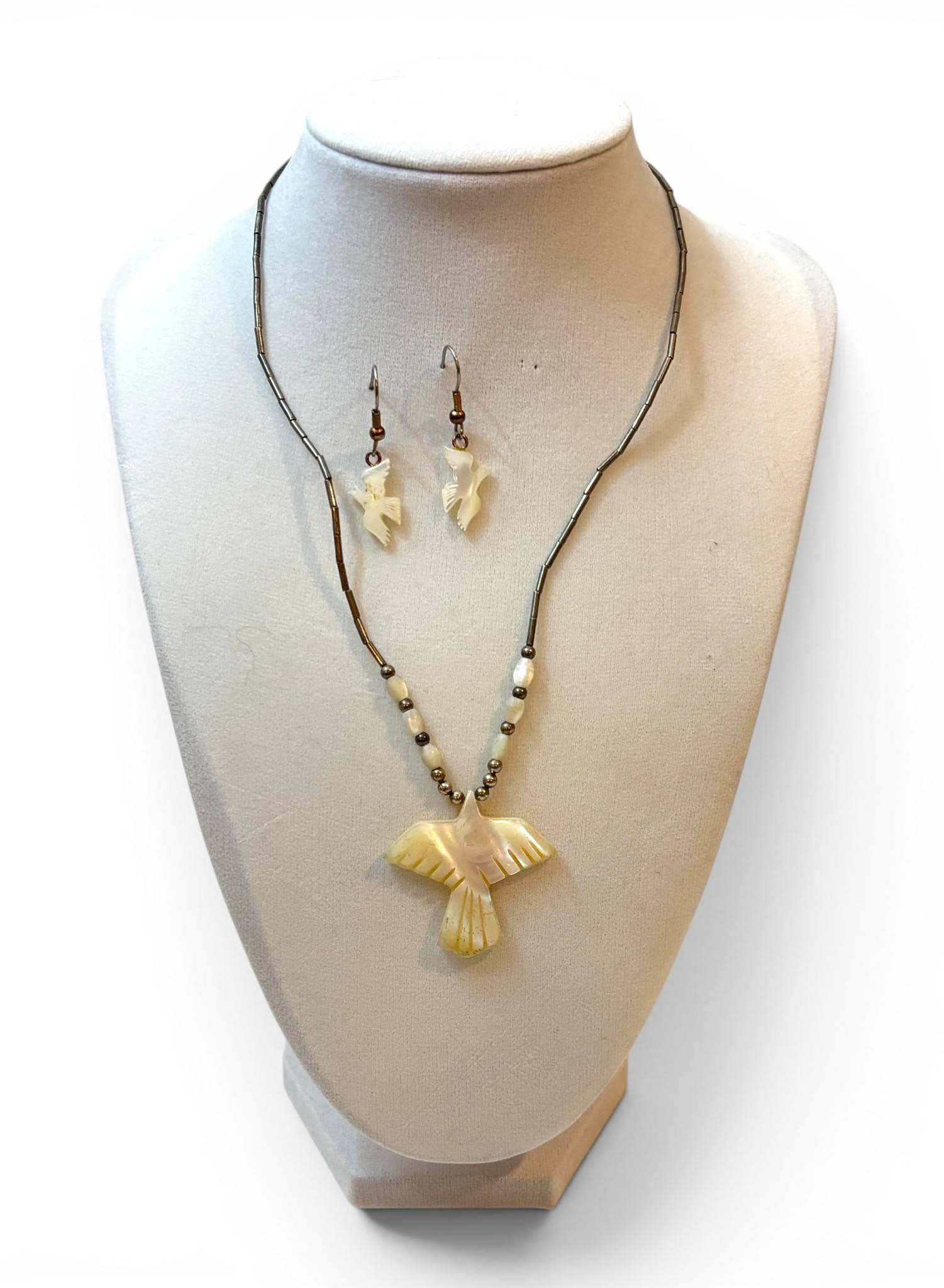 Sterling Silver Jewelry with Carved Bird Motif: Sterling silver jewelry set featuring a necklace and matching earrings. The necklace includes a carved bird-shaped pendant, strung with tubular and oval beads of varying tones, and a functional clasp.