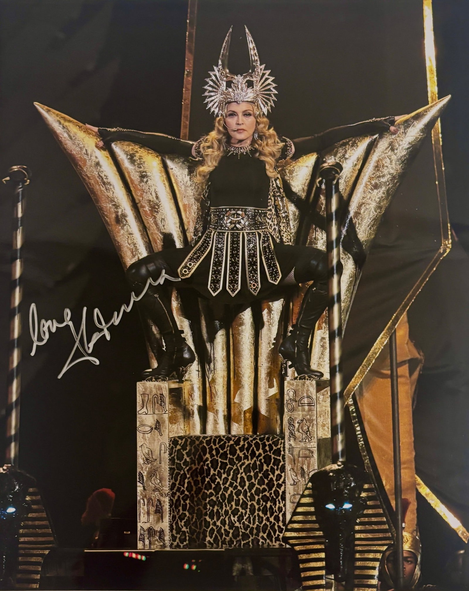 Madonna Signed Photograph From Super Bowl XLVI: Signed photograph of Madonna from her performance at Super Bowl XLVI, depicting the artist in an elaborate gold and black costume onstage. The signature reads Love Madonna in silver ink. Accompanied b