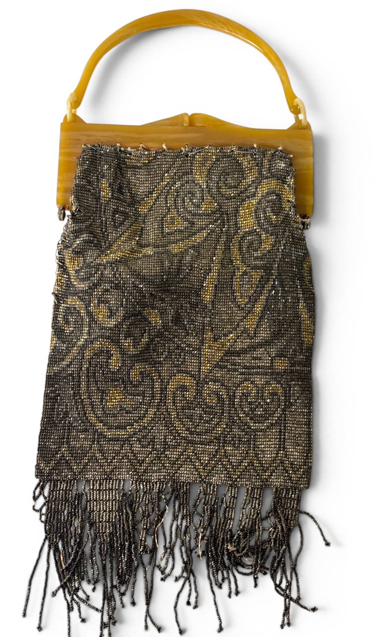 Antique French Beaded Purse with Bakelite Handle: Antique French purse featuring intricate glass beadwork in a swirling pattern, accented with a fringe design at the bottom. The top frame and handle are crafted from Bakelite in a warm amber color,