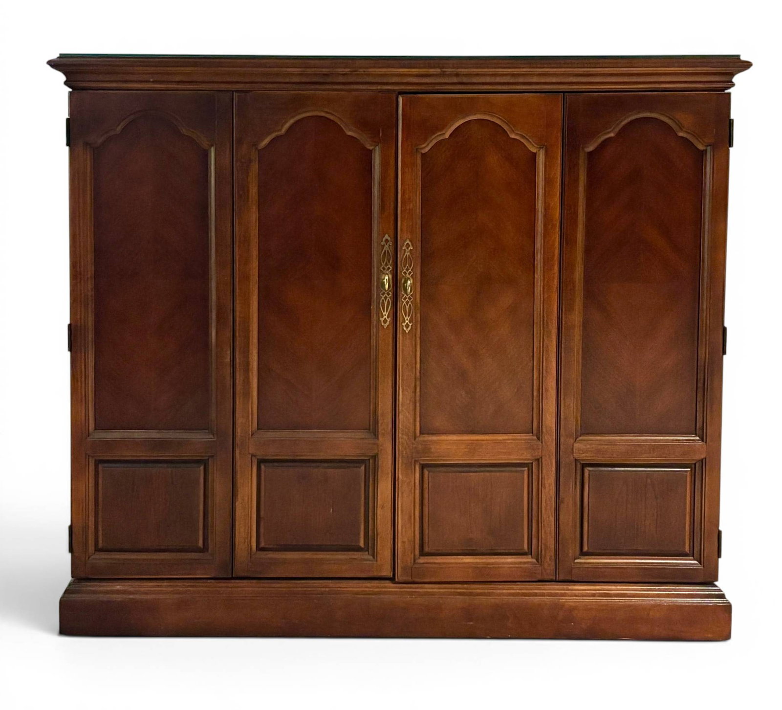 Wooden Entertainment Cabinet with Brass Hardware and Glass Top: A four-door wooden entertainment cabinet featuring brass hardware with decorative accents. The design includes interior shelving, a pull-out tray, and a recessed area for potential use with electronic