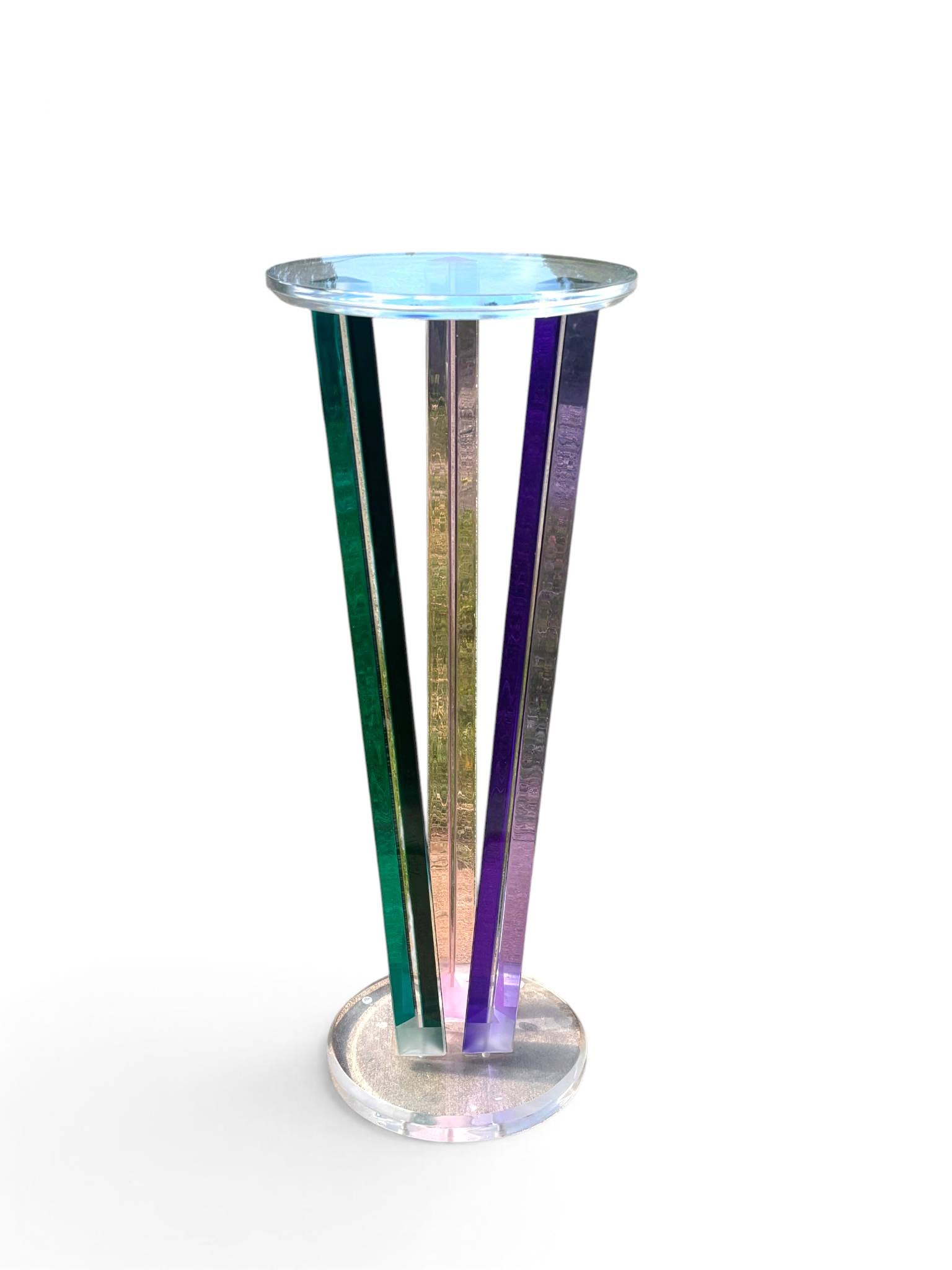 Shlomi Haziza Table with Multicolored Prism Legs: A sculptural pedestal table by Shlomi Haziza, featuring a circular clear Lucite top and base. Four multicolored prism-shaped vertical supports in green, purple, pink, and gold tones elevate the design