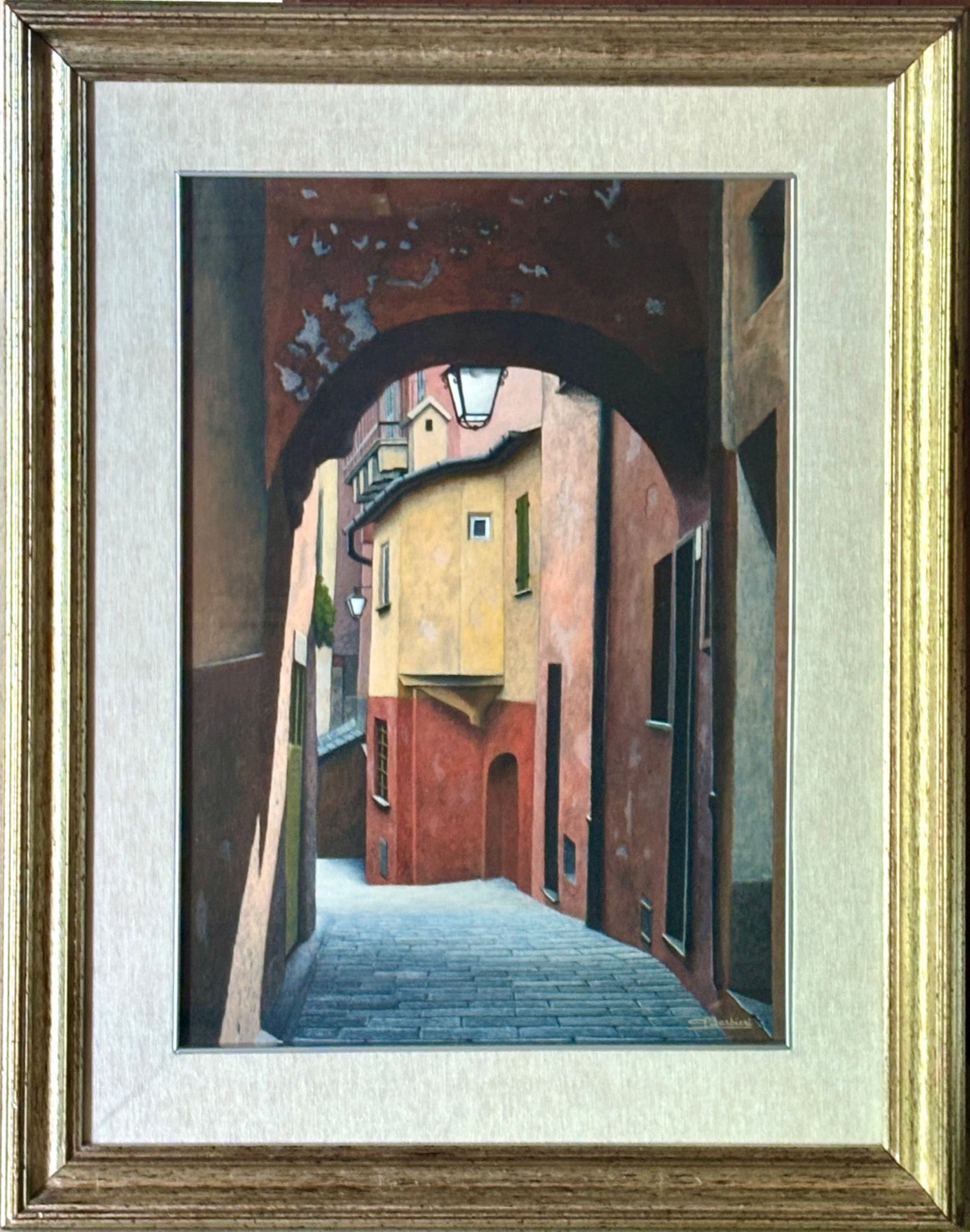 Arched Alleyway by E. Barbieri Framed Print: Oil painting on canvas depicting a narrow alleyway with an archway and colorful stucco buildings under soft lighting, signed by artist ‘E. Barbieri’ in the lower right corner. Encased in a gold-to