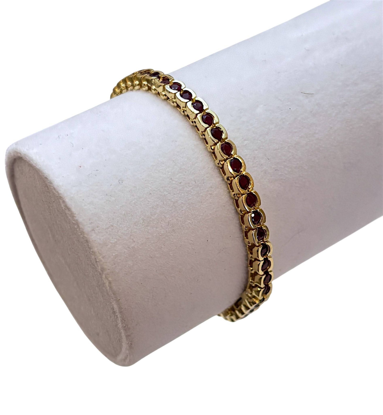14K Yellow Gold Ruby Tennis Bracelet with Box Clasp: A 14K yellow gold tennis bracelet featuring oval-cut rubies in bezel-like settings, forming a continuous, elegant design. The bracelet is secured with a box clasp, providing safety and durability. The