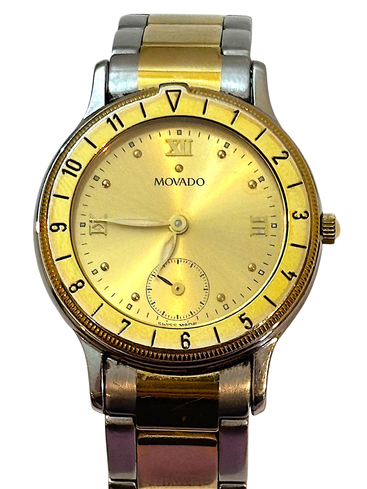 Movado ESQ Two-Tone Stainless Steel Quartz Wristwatch: Movado ESQ wristwatch featuring a two-tone stainless steel bracelet with gold-tone accents. The round gold-tone dial displays Roman numeral hour markers at the 12, 3, 6, and 9 positions, with addition