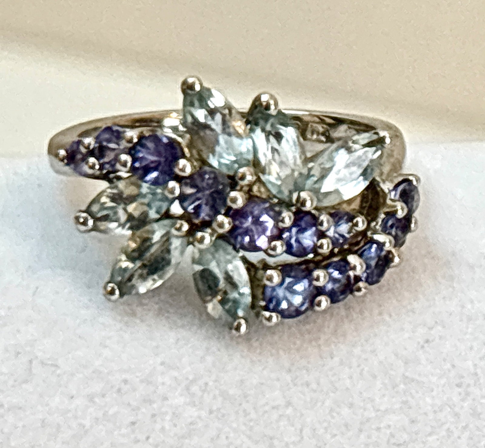 Sterling Blue Topaz and Tanzanite Cluster Ring: Sterling silver cocktail ring featuring a cluster of marquise-cut blue topaz and round-cut tanzanite stones arranged in an elegant floral-inspired design. Marked ‘925’ on the inner band indicating