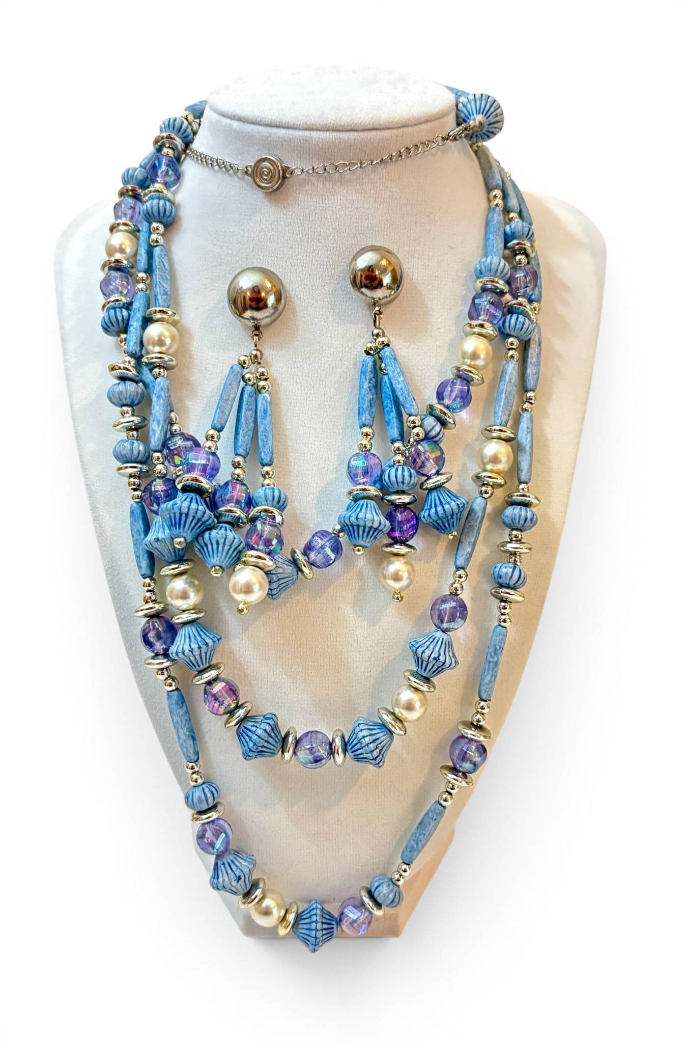 Vintage Blue Beaded Necklace andn Earrings Set: Vintage jewelry set featuring a multi-strand necklace and matching earrings. The necklace consists of light blue cylindrical and ribbed beads, translucent purple beads, faux pearls, and silver-toned