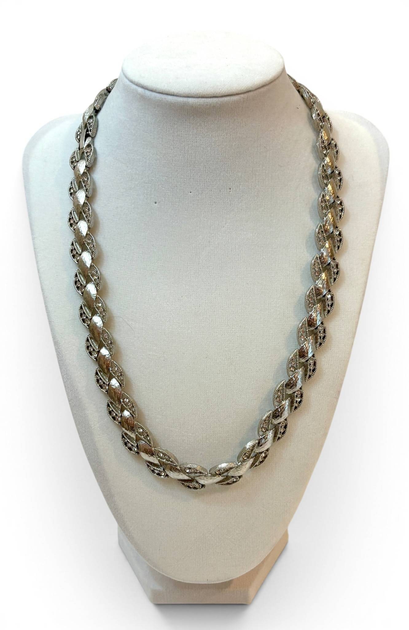 Vintage Nolan Miller Necklace with Textured Links: Silver-tone necklace designed by Nolan Miller, featuring interconnected textured links with alternating smooth and ridged surfaces. The clasp is marked ‘Nolan Miller,’ confirming the designer. In 