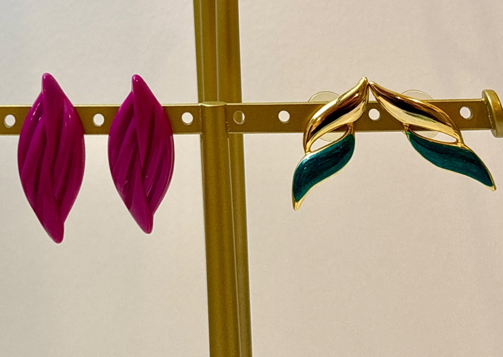 1980s Postmodern Earrings Set: 1980s vintage postmodern earrings consisting of two distinct designs. One set features bright pink acrylic in a twisted leaf silhouette. The other set consists of gold-tone earrings with green enamel