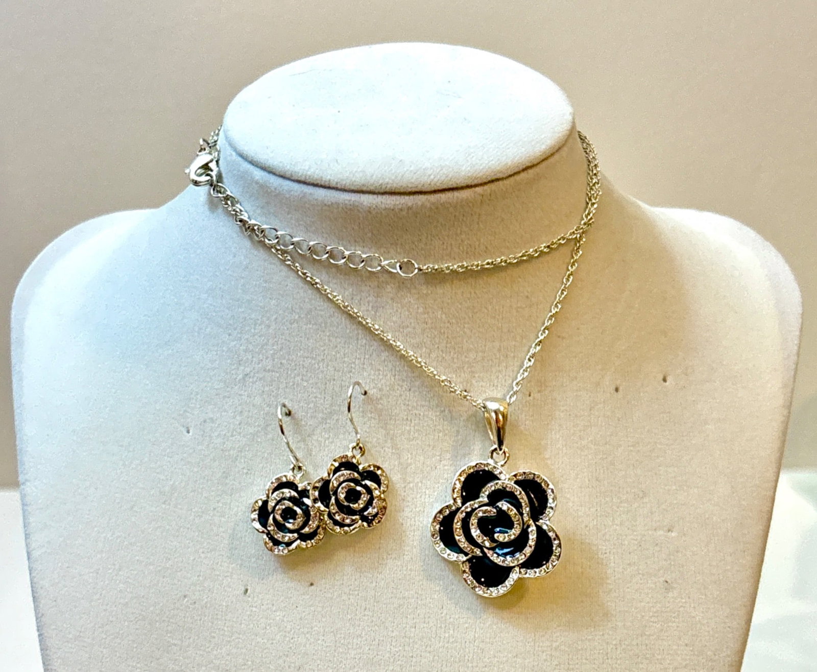 Black Rose and Rhinestone Jewelry Set: Jewelry set featuring a silver-tone necklace with a black rose pendant accented with rhinestones, paired with matching black rose dangle earrings with rhinestone detailing. The necklace has a lobster